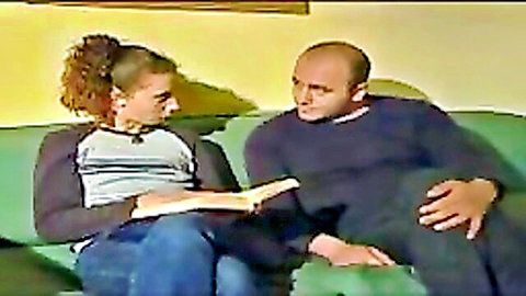 Italian couple in casual clothes reading book together on couch