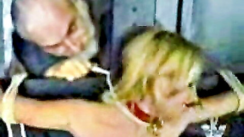 Bound blonde woman in red collar dominated by older man in punishment scene