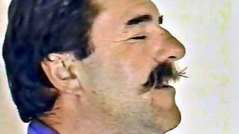Close-up of mature man with mustache smirking in purple shirt, convent porn teaser