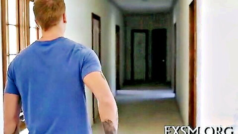 Blond man in blue shirt walks down hallway, teasing wild adult encounter