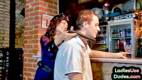 Dominant curly-haired babe collars submissive redhead dude at dimly lit bar counter