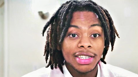 Close-up of Black man with dreadlocks, wide eyes, open mouth showing pink lips and teeth, wearing pink shirt