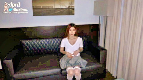 Asian woman with red hair in white V-neck top, gray pleated skirt, and lace stockings, sitting solo
