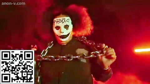 Masked redhead with chains in eerie red-lit fetish scene