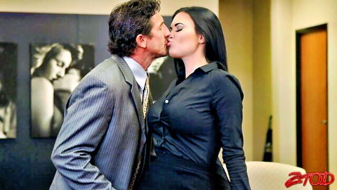 Older suited man passionately kissing busty raven-haired woman in black blouse