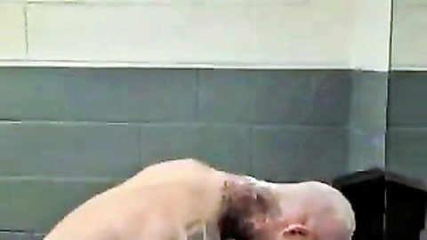 Nude woman bent over getting head shaved in restroom