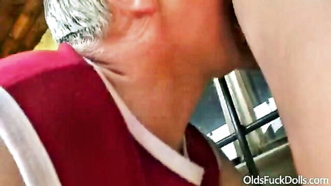 Older man with gray hair kisses young sportsgirl neck in red top