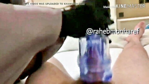 Black gloved hand using purple fleshlight masturbator on hard cock closeup