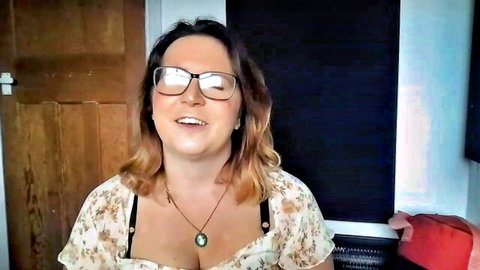 CassieBrookes smiling playfully in low-cut floral blouse with cleavage