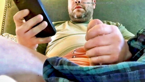 Bearded daddy holds phone filming his big hard cock and balls exposed from plaid pants