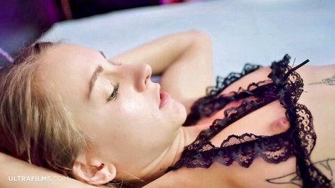 Blonde in black lace lingerie lying relaxed on bed, intense orgasms vibe