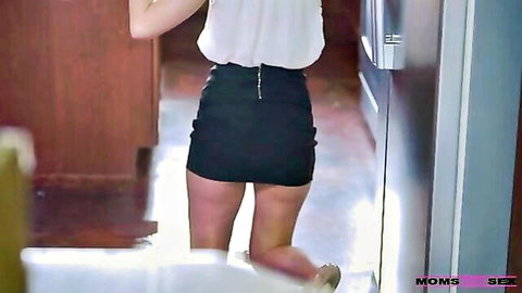 Mature woman in white blouse and black mini skirt bending over, showing legs and ass