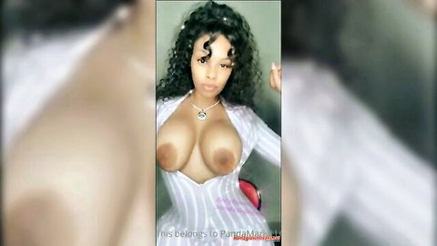 Curly-haired ebony woman exposing large breasts in open white top