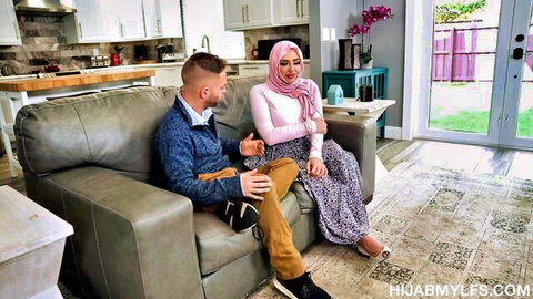 Hijab girl in pink hijab and skirt sits close with guy on couch flirting intimately