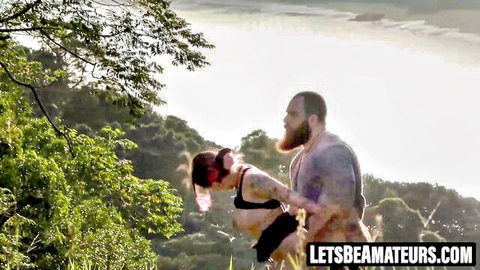 Naughty girl in bikini held upside down by bearded man during outdoor sex
