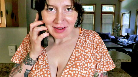 Bettie Bondage in low-cut floral dress, smiling on phone with cleavage tease