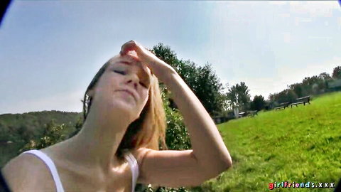 Blonde Alexis Crystal shielding eyes outdoors in white tank top, sunny field