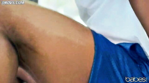 Muscular tanned guy in tight blue gym shorts teasing his bulge from side view