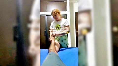 Blonde pedicurist massaging muscular male calf and foot on blue table in salon