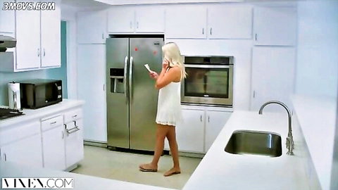 Blonde teen in short white dress on phone call in kitchen