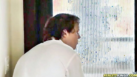 Chubby man in white shirt peeking through bedroom window blinds