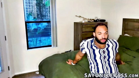 Trent Marx lounging on bed in striped shirt, teasing gay scene