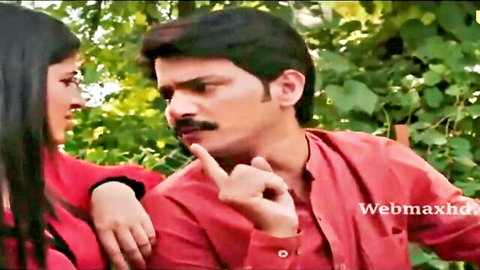 Indian couple in red outfits sharing intimate shushing moment outdoors