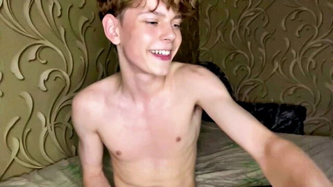 Smiling shirtless redhead twink exposes smooth chest on webcam solo
