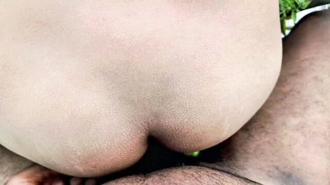 Close-up of pale woman's spread ass cheeks exposing tight pink anus and hairy pussy lips from behind.