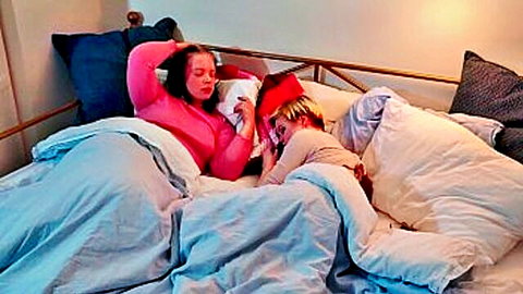 Woman and young boy reading book in bed together