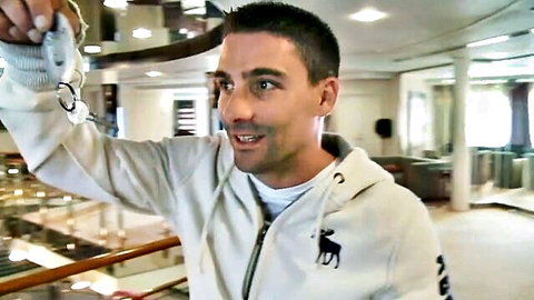 Athletic man in hoodie holds handcuffs on luxury boat for orgy fun