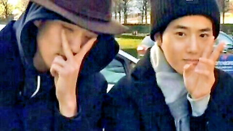 Two young Asian men posing playfully outdoors in coats and hats