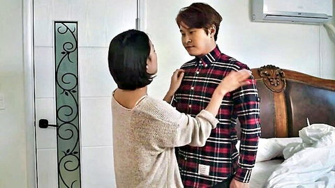 Asian woman intimately adjusting man's plaid shirt in close encounter