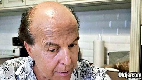 Bald old man in floral shirt staring intensely in kitchen on Oldjie.com
