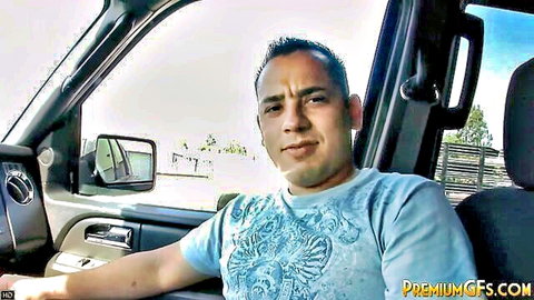 Hispanic man with serious expression sitting in truck driver's seat wearing blue graphic t-shirt