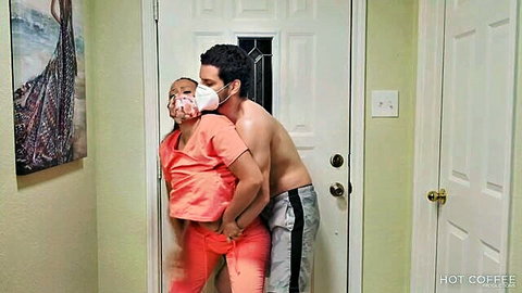 Masked nurse in pink scrubs pants down exposing big ass grabbed from behind by shirtless guy in sweatpants
