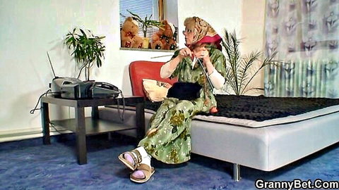 Lonely old grandma knitting in green floral dress on bed, mature seduction
