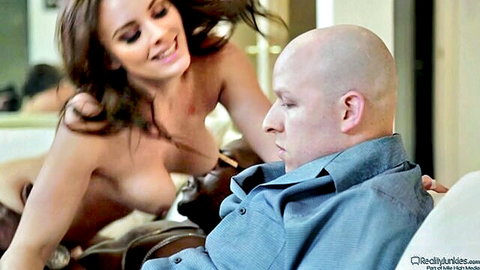 Topless skinny brunette with small tits shoves bare breasts into bald man's shocked face on couch