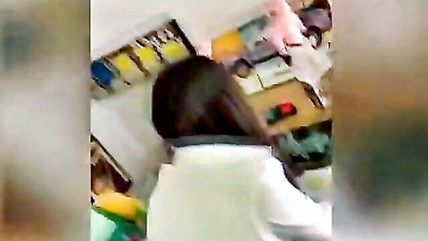 Brunette teen student bending over desk in colorful classroom from behind