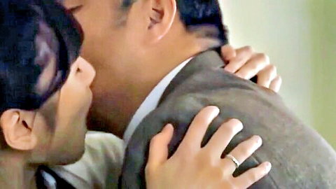 Passionate kiss between young Japanese woman and mature suited man embracing tightly