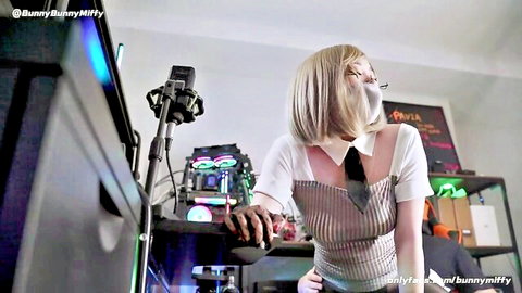 Blonde gamer girl in white blouse and tie seduces on gaming setup, pantyhose tease