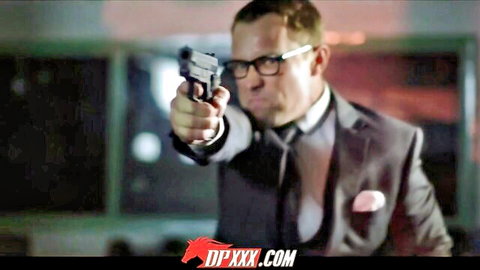 Suited man in glasses pointing gun in intense action scene