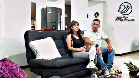 Latina couple in tight clothes sitting close on couch in living room