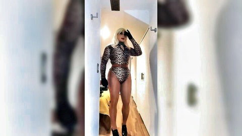Blonde crossdresser in leopard bodysuit seduces in doorway, teasing pose