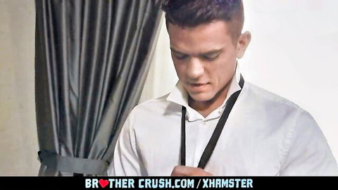 Handsome young stepbrother in white shirt looks down intently in taboo gay Brother Crush scene
