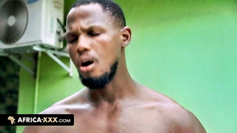 Muscular black gym coach EboBlack shirtless, intense expression in gym