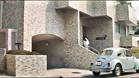 Woman in white uniform on outdoor stairs near vintage VW Beetle, brutal BDSM (1980)