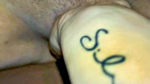 Close-up of man's hairy thigh with 'Sil' tattoo and erect penis in squirting scene