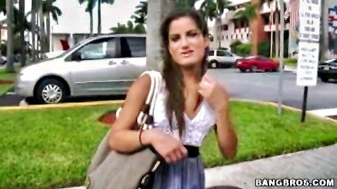 Sexy brunette Latina in low-cut top and skirt outdoors, teasing cleavage