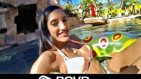 Smiling young brunette with small tits in white bikini floating on pool ring selfie